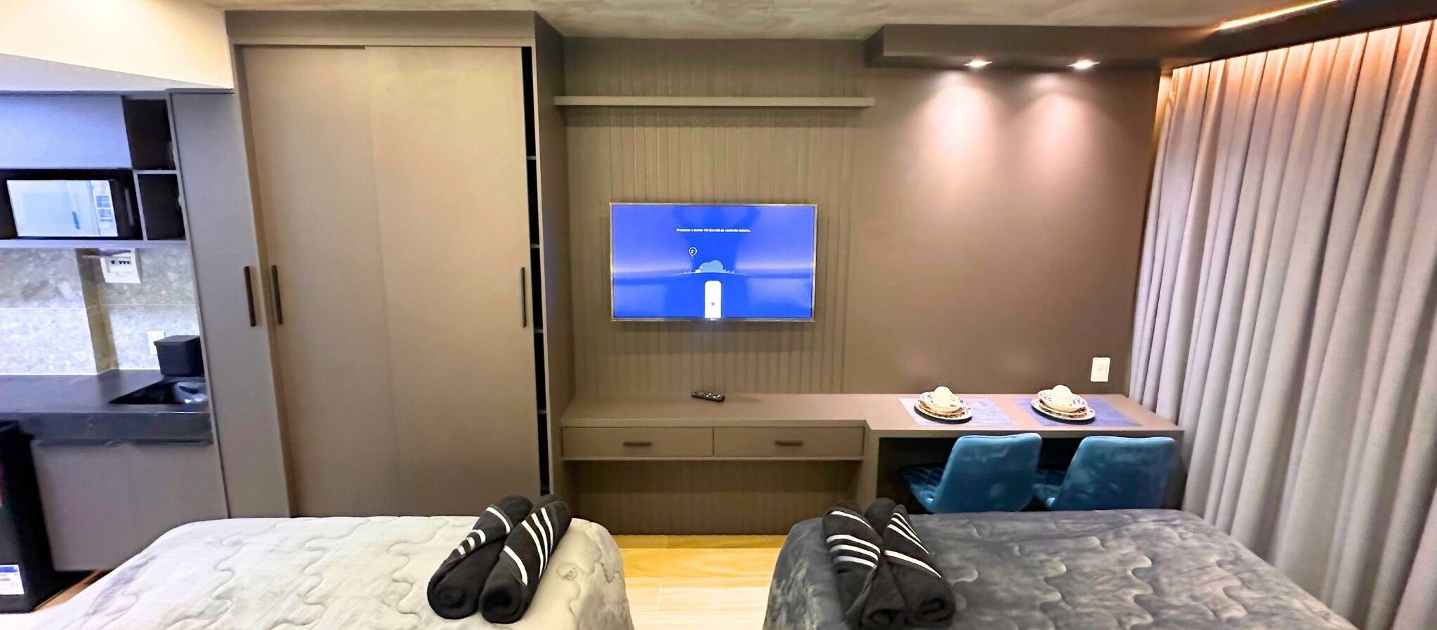 Una habitación de hotel con cama, escritorio con televisor y área de comedor con sillas.