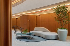 Un intérieur moderne avec un canapé aux lignes courbes, une table basse en verre, une chaise en métal et une grande plante en pot.