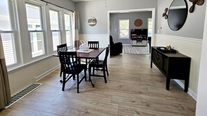 Un coin repas avec une table et des chaises en bois, un ventilateur de plafond et un téléviseur en arrière-plan.