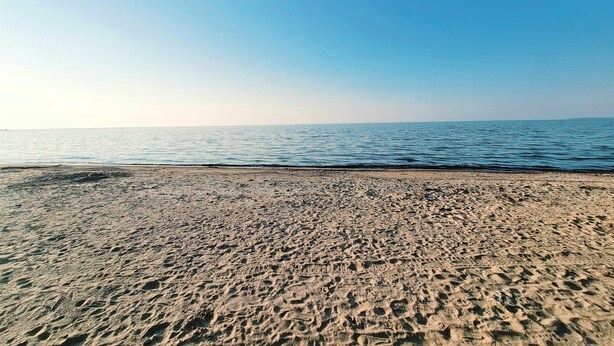 Une plage avec un ciel dégagé et une mer calme.