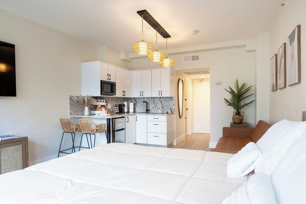 A modern bedroom with a large bed, a kitchenette, and a dining area. - Beach Front Beautiful New Apartment with Pool in Miami Beach. (Miami Beach)