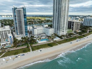 A coastal cityscape with high-rise buildings, a beach, and a marina. - Beach Front Beautiful New Apartment with Pool in Miami Beach. (Miami Beach)