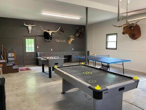 Um quarto com mesa de pebolim, mesa de bilhar e caveiras de animais fixadas na parede.