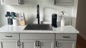 A kitchen with a sink, cabinets, and a coffee maker.