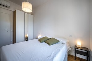 Un dormitorio con cama, mesitas de noche, armario y lámpara colgante.