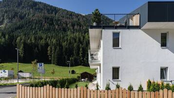 A modern building with a balcony, a parking sign, and a mountainous backdrop.