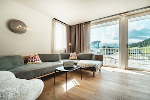 A modern living room with a sofa, a coffee table with a laptop, and a view of a mountainous landscape through large windows. - Holiday Apartment in a Hotel 'Apartment Harmony' with Mountain View, Shared Garden and Wi-Fi (Sesto)