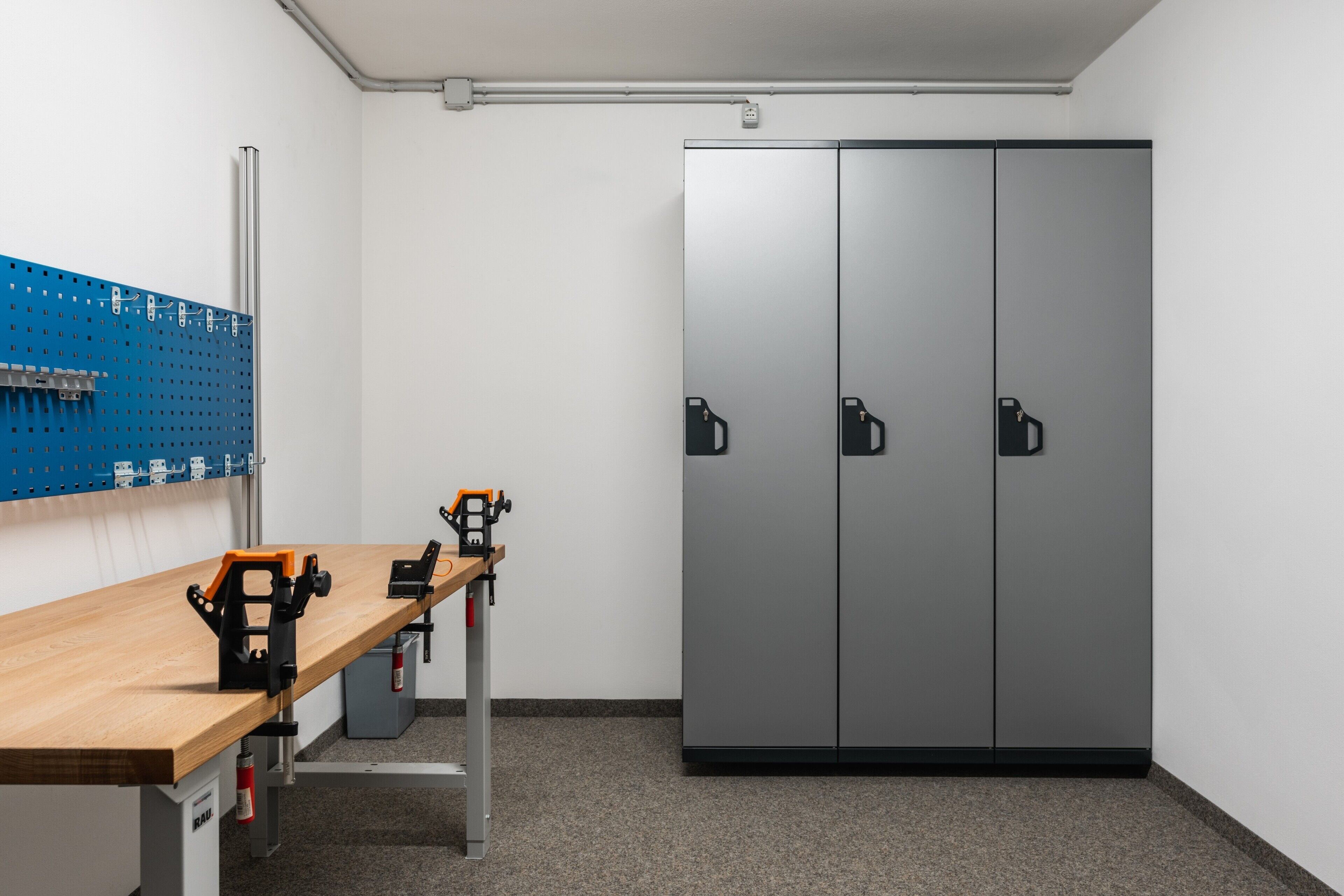 A room with a workbench, pegboard, and a large wardrobe.