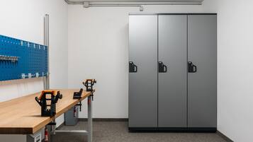 A room with a workbench, pegboard, and a large wardrobe.