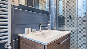 Une salle de bain moderne avec un meuble-lavabo en bois, un grand miroir et une cabine de douche en verre.