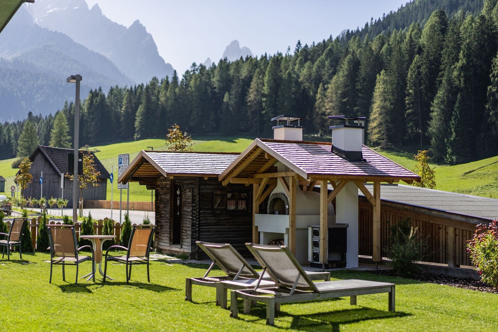 Ein Chalet mit Holzwand, Sitzgelegenheit im Freien und Blick auf eine Berglandschaft.