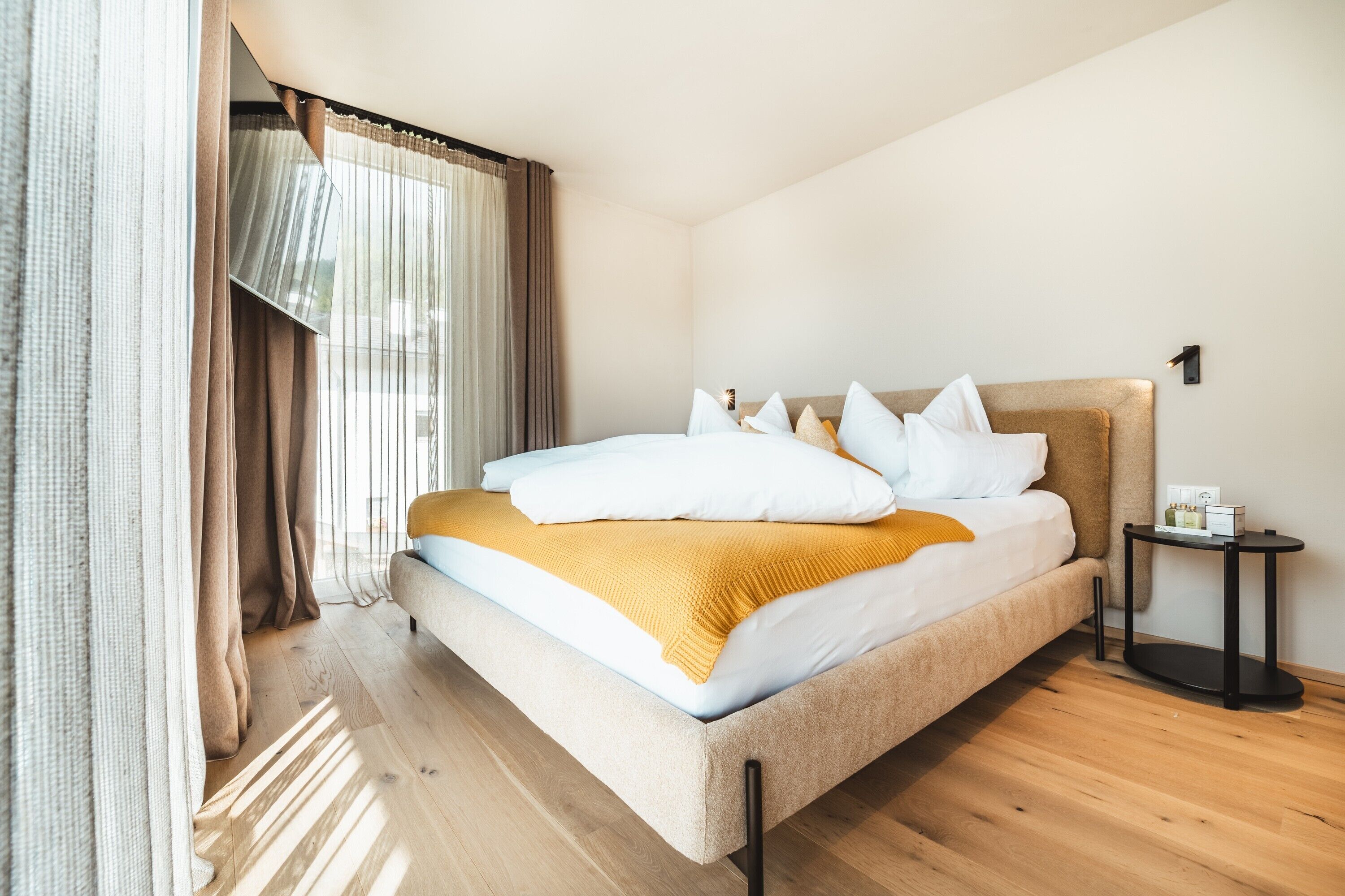Une chambre d’hôtel moderne avec un grand lit, une table de chevet et une fenêtre avec des rideaux.