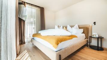Une chambre d’hôtel moderne avec un grand lit, une table de chevet et une fenêtre avec des rideaux.