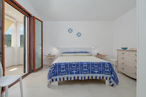 Een slaapkamer met een bed, een dressoir, een stoel en een raam met uitzicht.