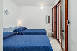 Een hotelkamer met twee bedden, een bureau, een stoel, een spiegel en een kledingkast met schuifdeuren.