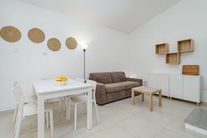 Een moderne woonkamer met een witte tafel, een bruine bank en een klein houten tafeltje.