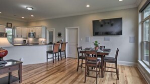 A modern kitchen with white cabinets, a central island, and a dining area with a table and chairs.