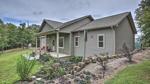 A two-story house with a covered porch, a front yard with a garden, and a gravel driveway.