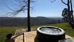 A hot tub on a wooden deck with a view of mountains.