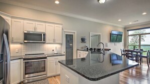 A modern kitchen with white cabinetry, stainless steel appliances, and a large island.