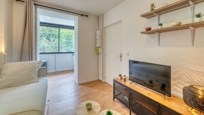 A modern living room with a sofa, TV, and shelves with plants. - Le Petit Gerland - Agréable à 1 minute du métro B (Lyon)