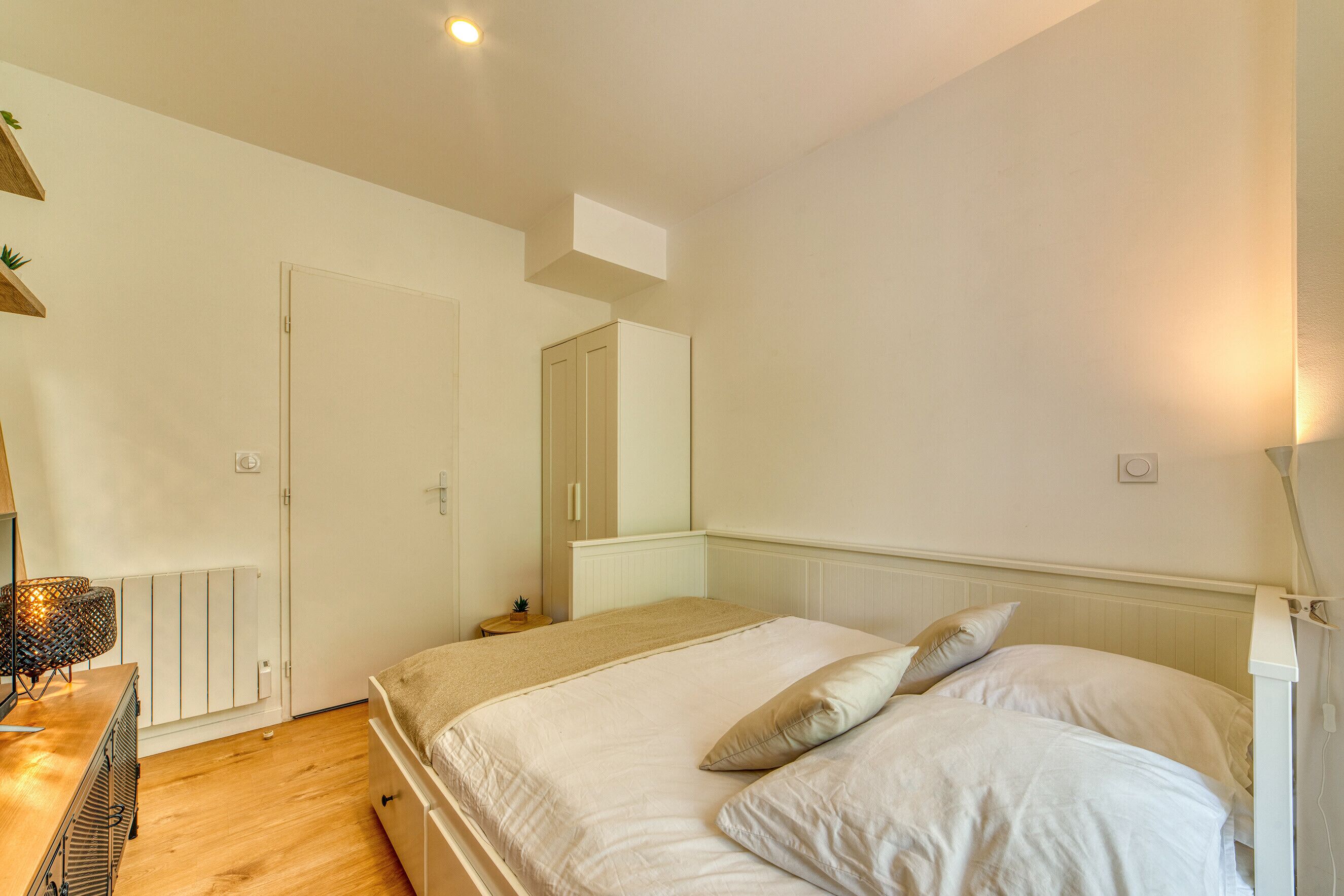 Une chambre à coucher comprenant un lit, une commode, un radiateur et une armoire.