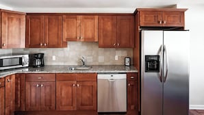 Une cuisine moderne avec des meubles en bois, un réfrigérateur en acier inoxydable, un lave-vaisselle, un four à micro-ondes et une machine à café.