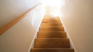 Un escalier en bois avec une rampe, qui monte.