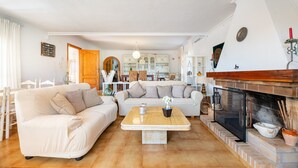 Una sala de estar con sofá, mesa de centro, chimenea y cocina al fondo.