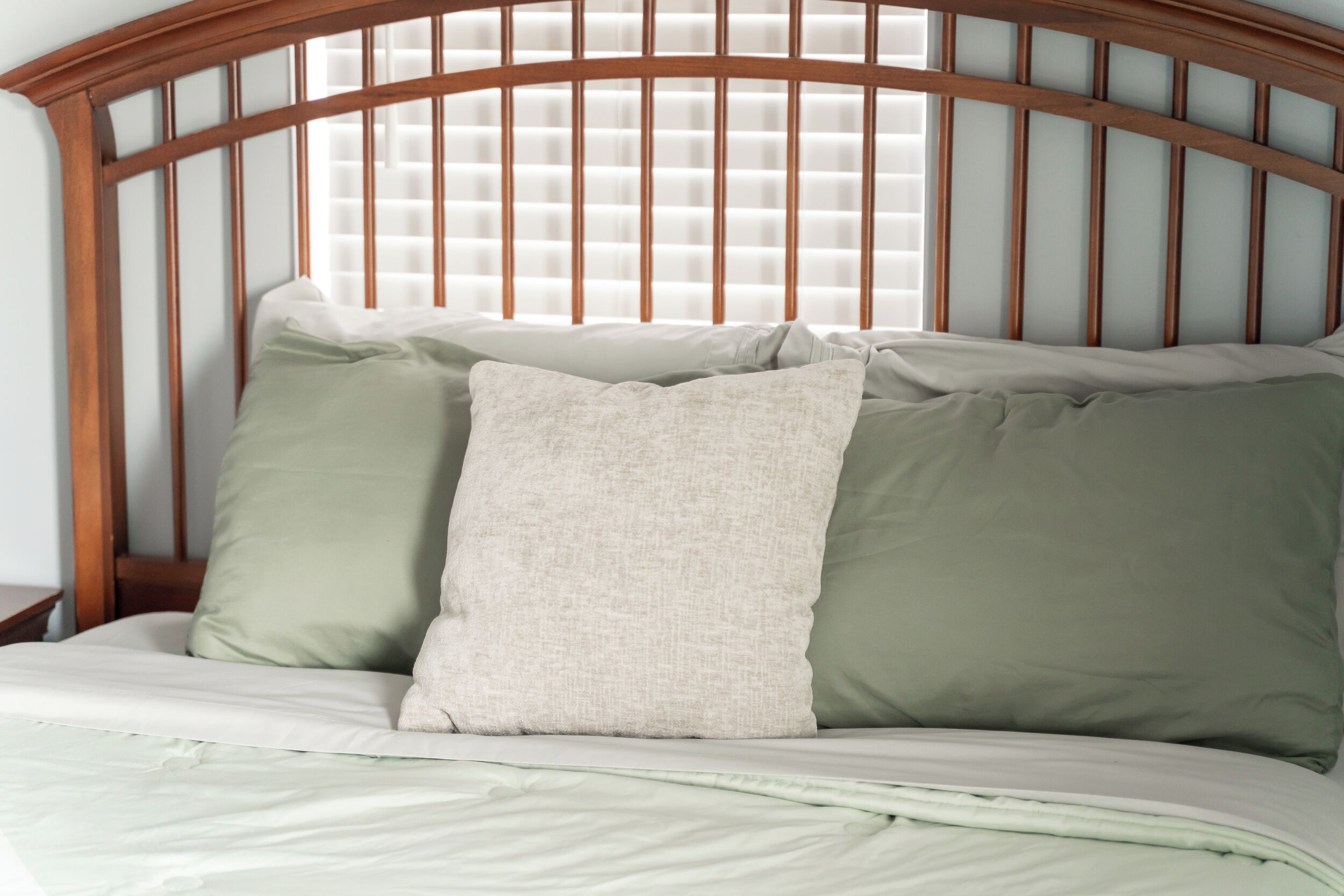 A bed with a wooden headboard, two pillows, and a white bedspread.