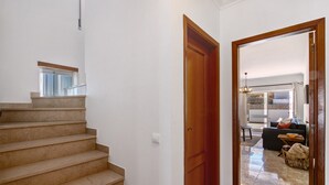 Eine Treppe führt zu einem Wohnbereich mit einer Holztür, einem Fenster und einem Fliesenboden.