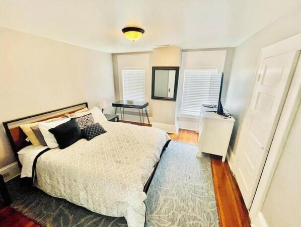 Cozy retreat with a neatly made bed, compact desk, and mirror.