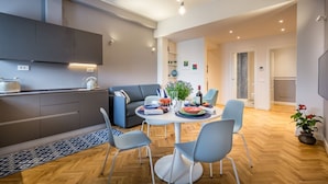 A modern kitchen with built-in appliances, a dining area with a round table and chairs, and a living space with a sofa and a coffee table. - Apartments Florence - Cobalt Cove 2bdr (Florence)