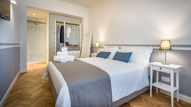 A hotel room with a bed, bedside tables, a wardrobe, and a bathroom visible through an open door. - Apartments Florence - Cobalt Cove 2bdr (Florence)