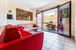 A living room with a red sofa, a glass table, a patterned sofa, and a large painting on the wall. - Holiday Home 'Magy House' with Private Terrace (Quartu Sant'elena)