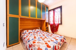 A bedroom with a bed, a wardrobe, and a window with curtains.