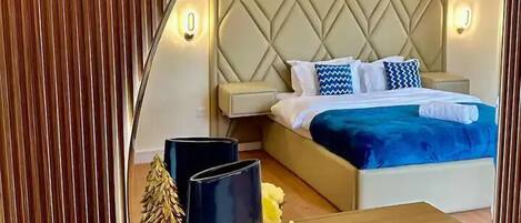 A bedroom with a bed, bedside tables, and a mirror reflecting the room.