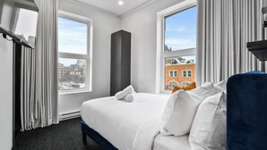 Une chambre d’hôtel avec un grand lit, une vue sur les immeubles et une fenêtre avec des rideaux.