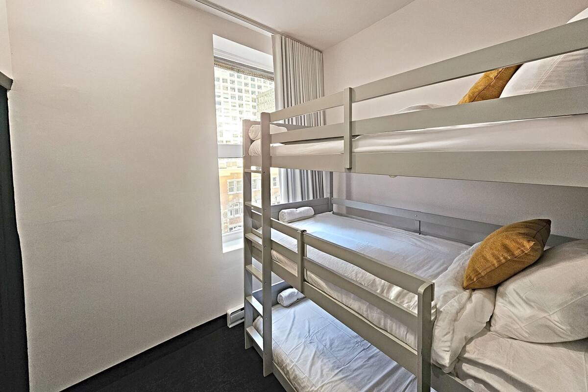 A bunk bed room with a window, white walls, and a black floor.