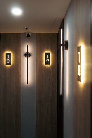 A modern hallway with wooden paneling and illuminated room numbers 10 and 19. - Lift Hotel (Montreal)