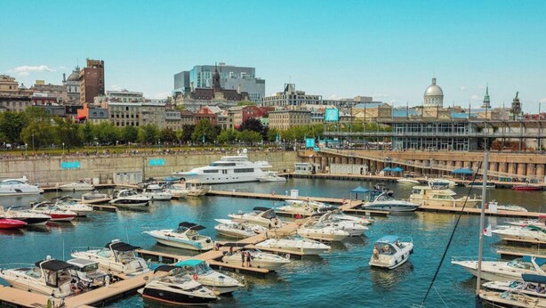 Un port de plaisance où sont amarrés différents types de bateaux, un pont et une vue sur la ville, avec des bâtiments historiques en arrière-plan.
