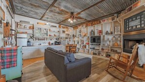 A rustic living room with a sofa, wooden rocking chair, and a dining area with a table and chairs.