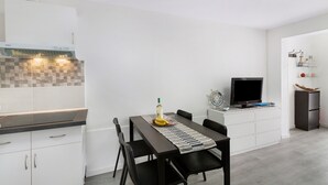 A modern kitchen with white cabinetry, a checkered backsplash, a dining table with chairs, a TV, and a refrigerator. - Holiday Apartment 'Bungalow Josephin' with Shared Pool, Private Terrace and Wi-Fi (Patalavaca)