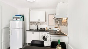 A compact kitchen with a refrigerator, microwave, washing machine, and a dining area with a table and chairs. - Holiday Apartment 'Bungalow Josephin' with Shared Pool, Private Terrace and Wi-Fi (Patalavaca)