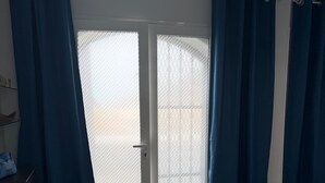 A room with a sliding glass door, a wooden floor, and a dark blue curtain. - Holiday Apartment 'Bungalow Josephin' with Shared Pool, Private Terrace and Wi-Fi (Patalavaca)