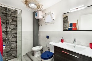 Ein Badezimmer mit Dusche, Toilette, Waschbecken und Spiegel.