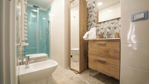 A modern bathroom with a glass shower enclosure, a wooden vanity with a mirror, and a white sink.