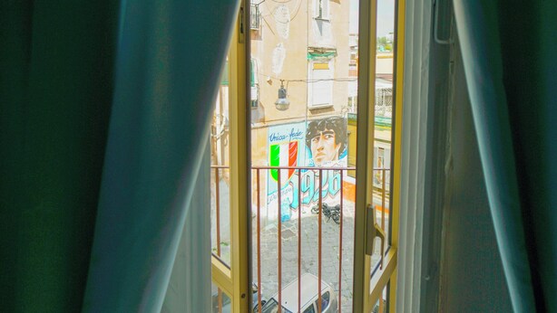 A doorway leading to an outdoor area with a metal gate and a view of buildings and a street.