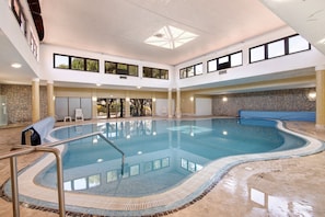 Ein überdachter Innenpool mit Steinwand und hoher Decke mit Oberlichtern.