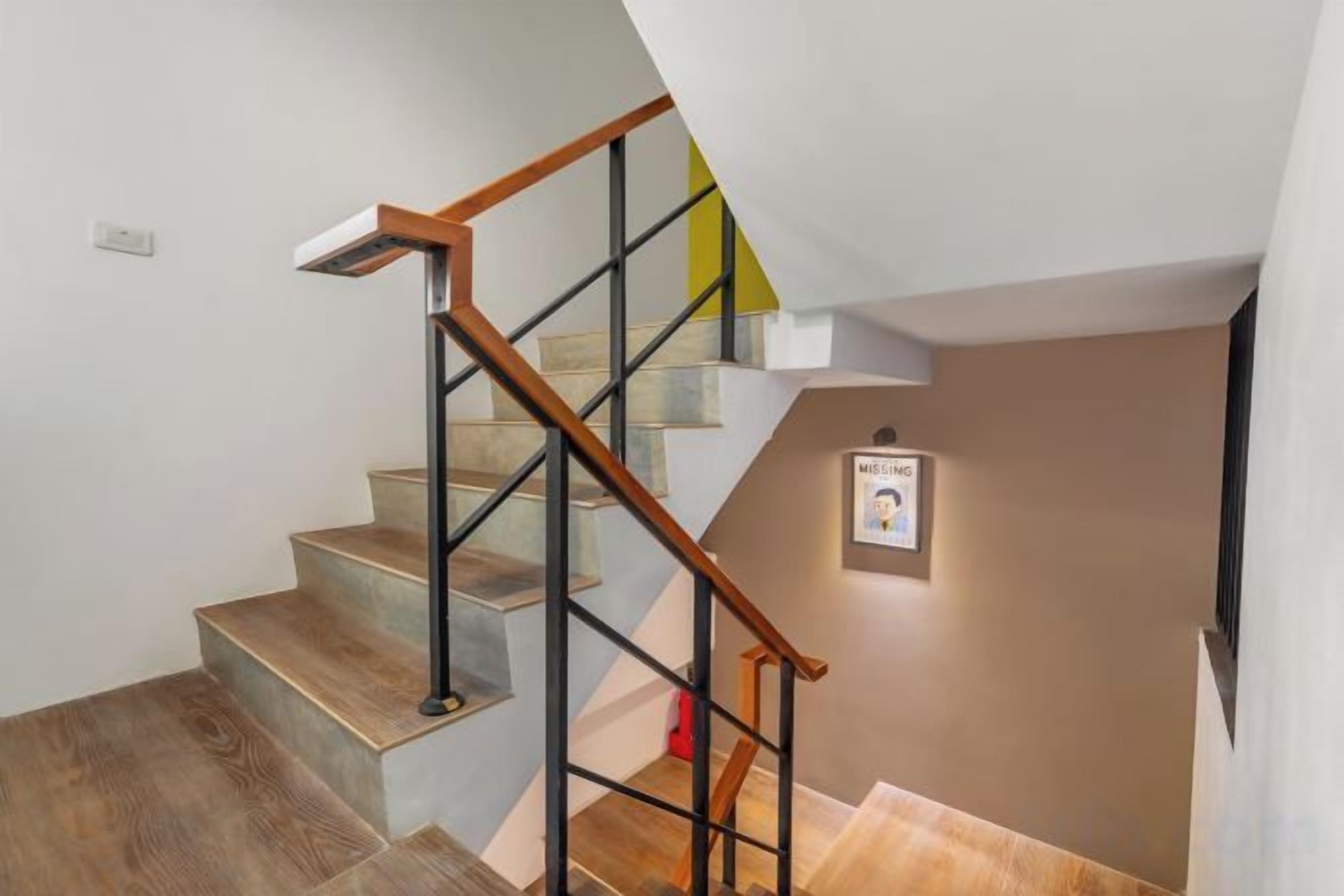 A staircase with wooden handrails and metal balusters, leading to a landing with a framed picture.